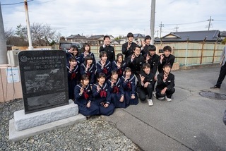 記念碑と集合写真を撮る様子