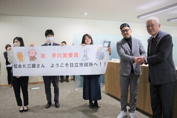 横断幕とともに職員の歓迎を受ける松永K三蔵さん