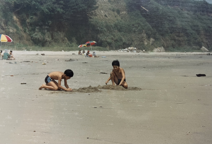 写真:久慈浜海水浴場で遊ぶ幼い頃の松永さん(写真左)